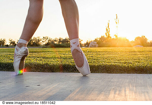 Feet of ballet dancer in pointe shoes at sunset with rainbow