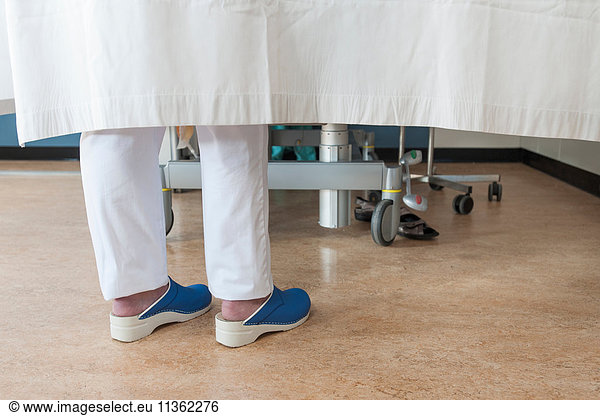 Feet of nurse behind hospital room privacy curtain