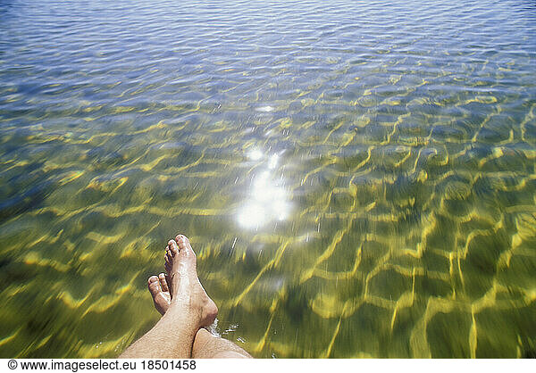 Feet over sparkling  clear ocean water.