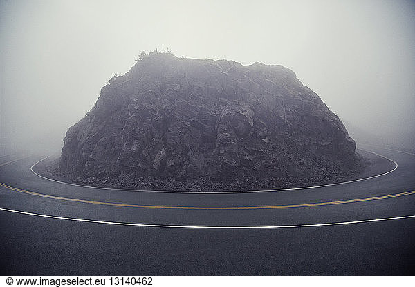 Felsformation inmitten einer Landstraße bei nebligem Wetter