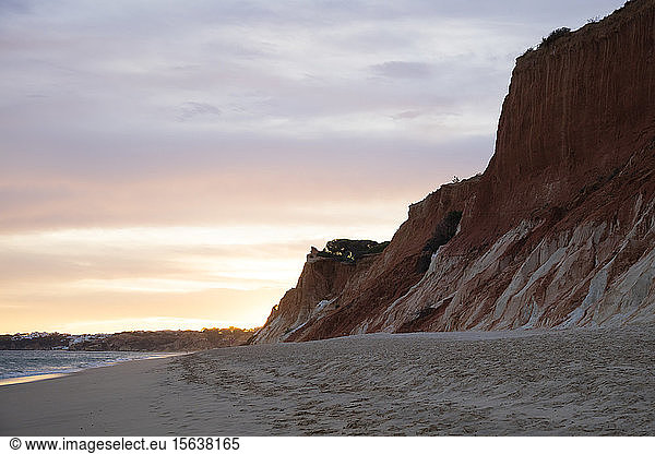 Felsiger Sandstein an der Atlantikküste vor bewölktem Himmel bei Sonnenuntergang  Algarve  Portugal