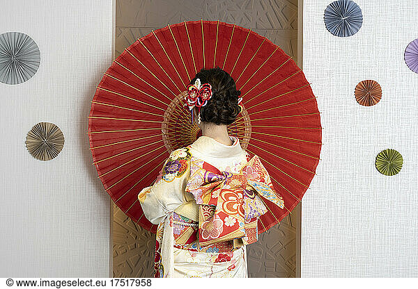 Female adult in kimono with an umbrella spread