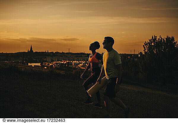 Female and male athlete walking on land during sunset