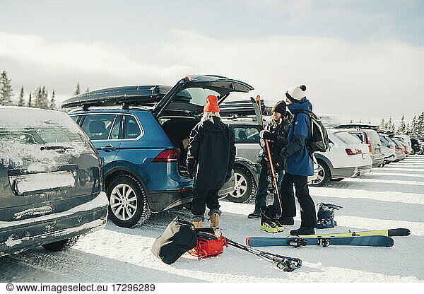 Female and male friends loading skis in trunk car during winter