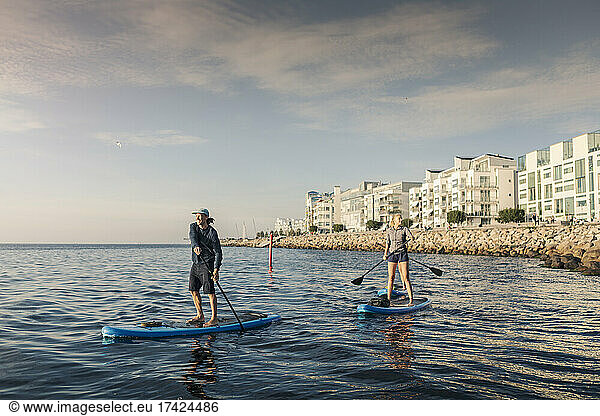 Female and male friends paddleboarding in sea