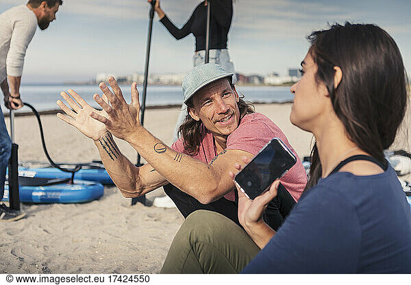 Female and male friends talking at beach during vacation