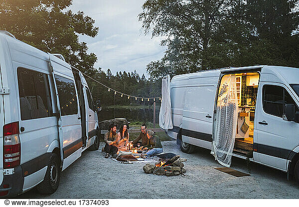 Female and male friends talking while spending leisure during camping