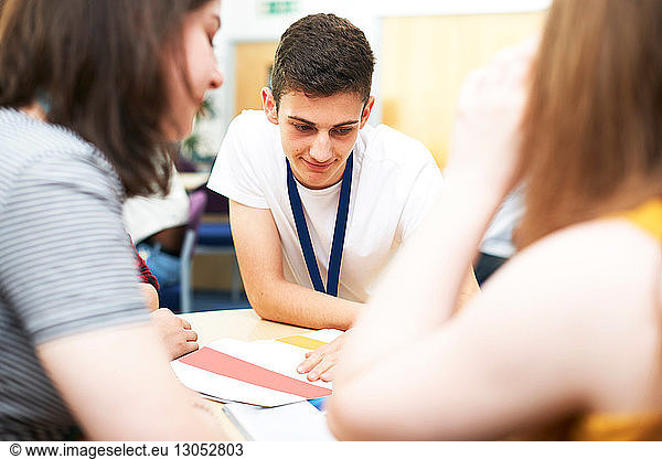 Female and male higher education students studying in college classroom  over shoulder view