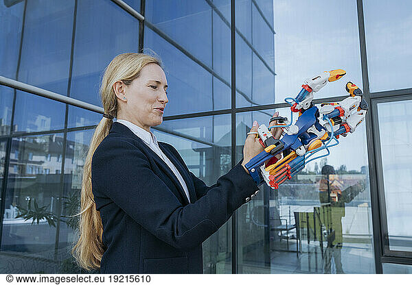 Female architect holding robotic arm near office building
