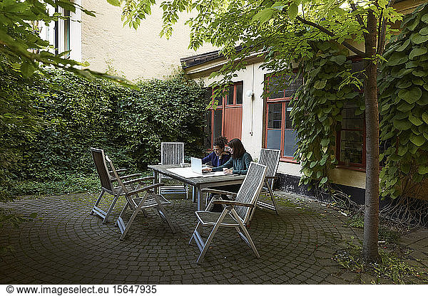 Female architects planning over laptop at table in backyard