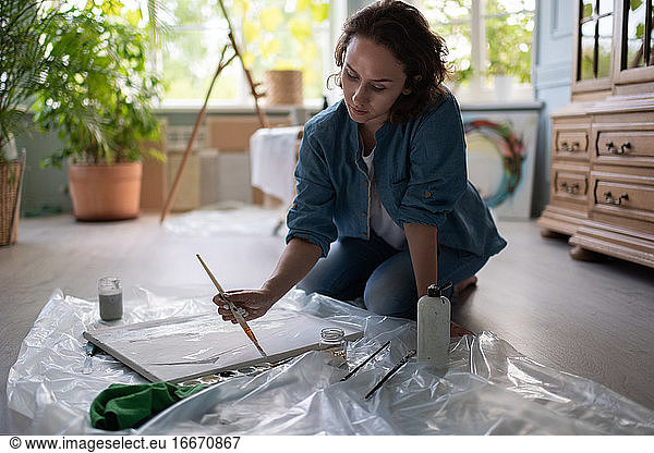 Female artist creating artwork on floor