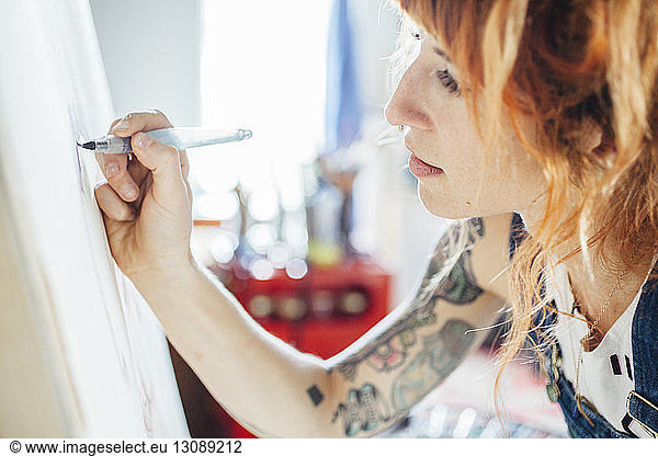 Female artist drawing sketch on canvas in studio