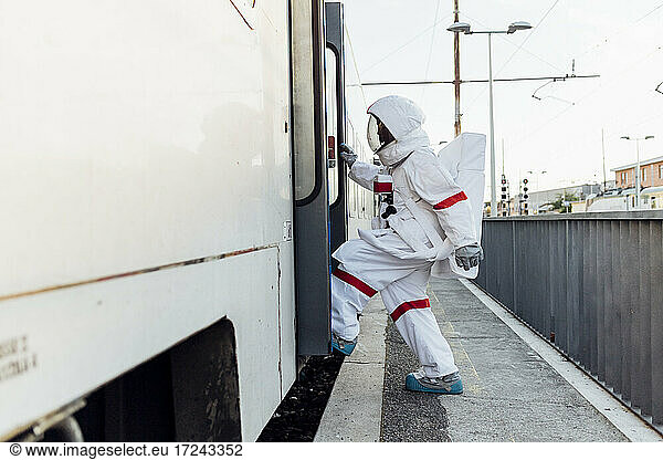 Female astronaut with space suit entering train at railroad station