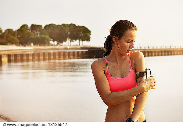 Female athlete adjusting arm band at beach