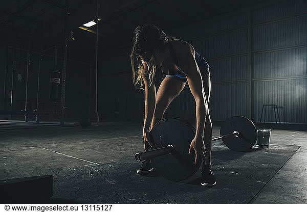 Female athlete adjusting barbell in gym