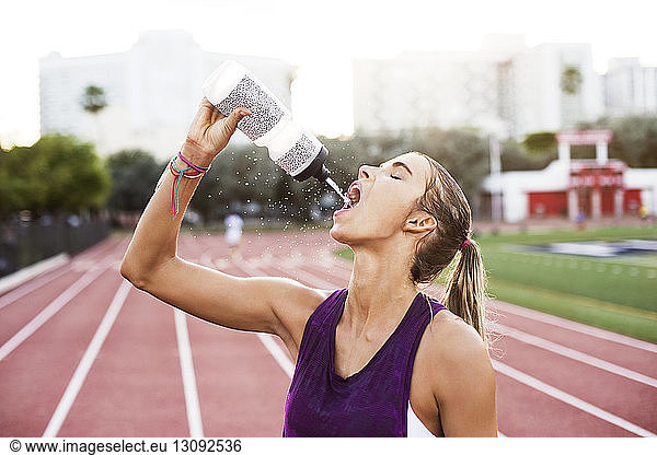 Female athlete drinking water on race tracks