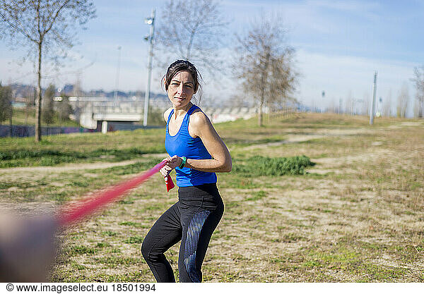 Female athlete exercising with resistance band on grassy field