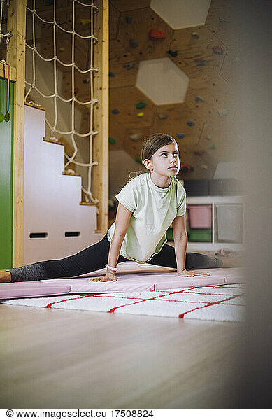 Female athlete looking away while doing stretching exercise at home