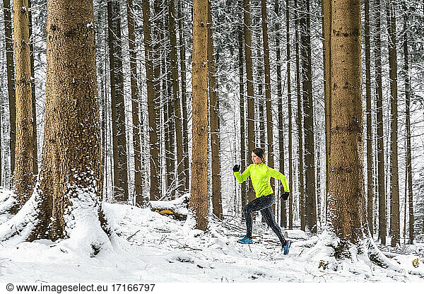 Female athlete running amidst trees during winter