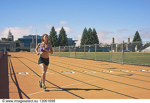 Female athlete running on track against sky