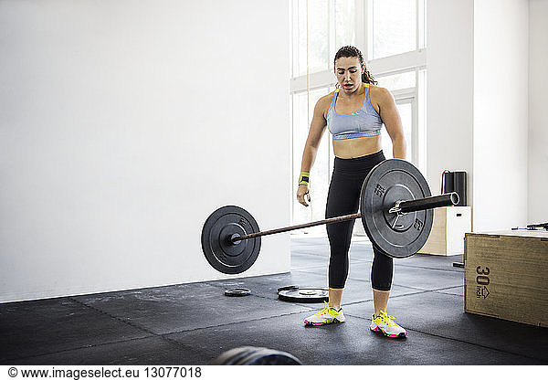 Female athlete throwing barbell in crossfit gym