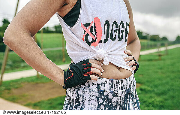 Female athlete with knotted shirt posing