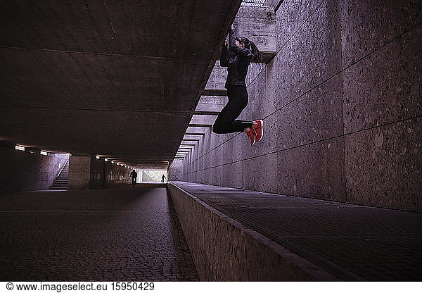Female athlete working out in a pedestrian underpass  doing chin-ups