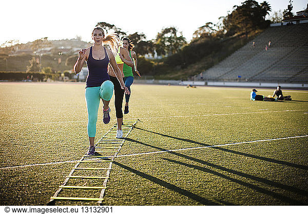 Female athletes training with agility ladder on sports field