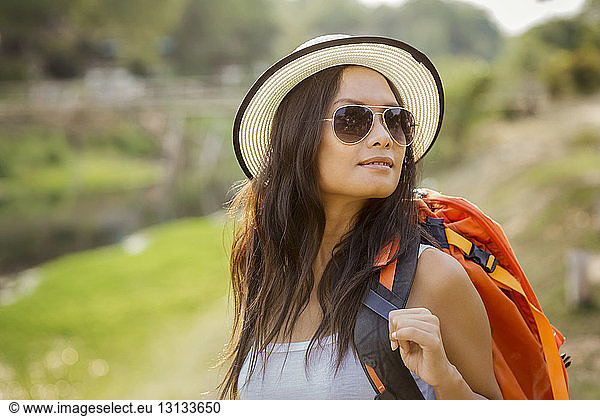 Female backpacker in sun hat and sunglasses on field