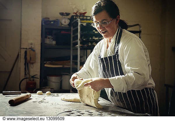 Female baker preparing bread dough in commercial kitchen
