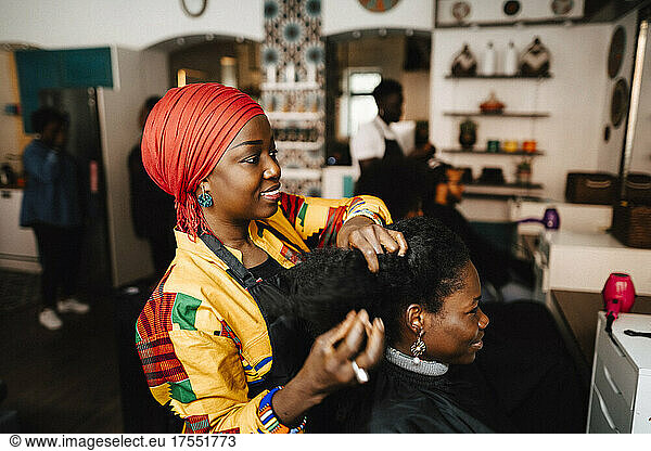 Female barber making hairstyle of customer in hair salon