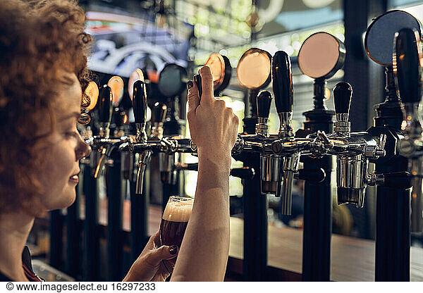 Female barkeeper tapping beer in a pub