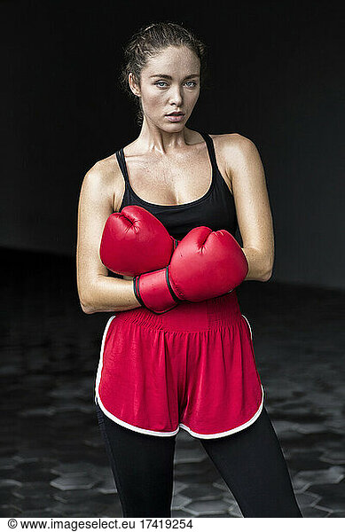 Female boxer with arms crossed standing at basement
