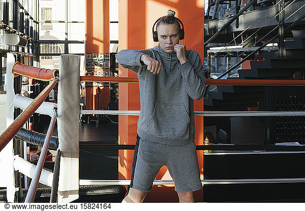Female boxer with headphones exercising in ring