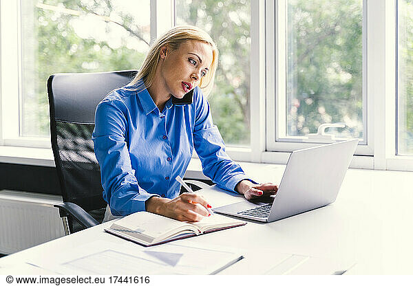 Female business professional talking on smart phone while working in office