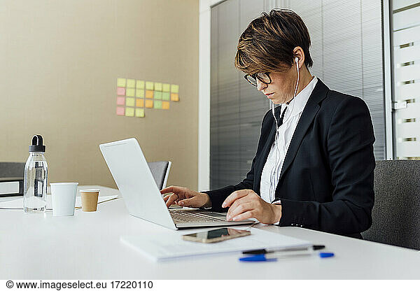 Female business professional using laptop at desk in office