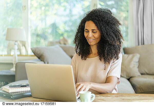 Female businesswoman working on laptop while sitting in living room at home