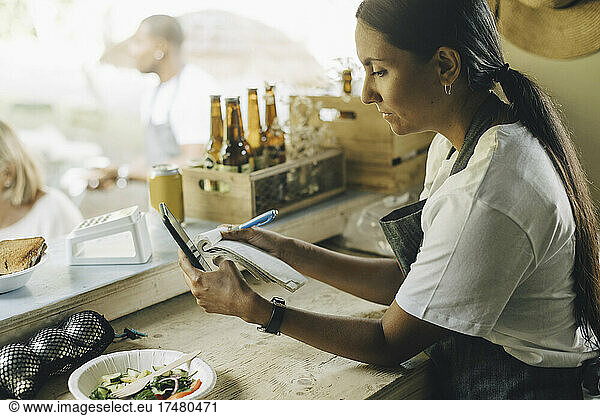 Female calculating bill on smart phone while working in food truck