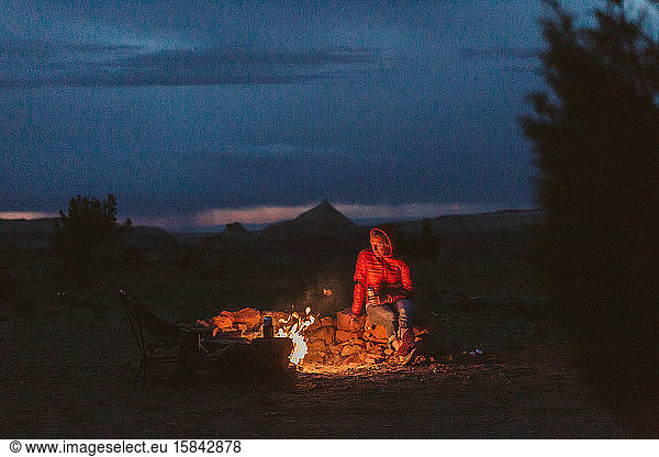 female camper drinks a beer around a campfire near moab utah