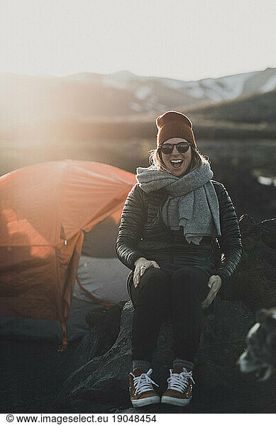 female camper laughs out loud on a cold sunset camping