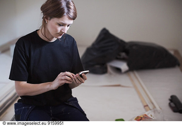 Female carpenter using mobile phone at site