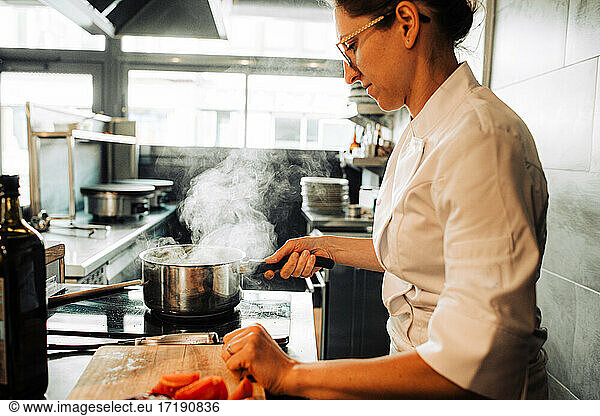 Female chef in uniform cooking in restaurant kitchen