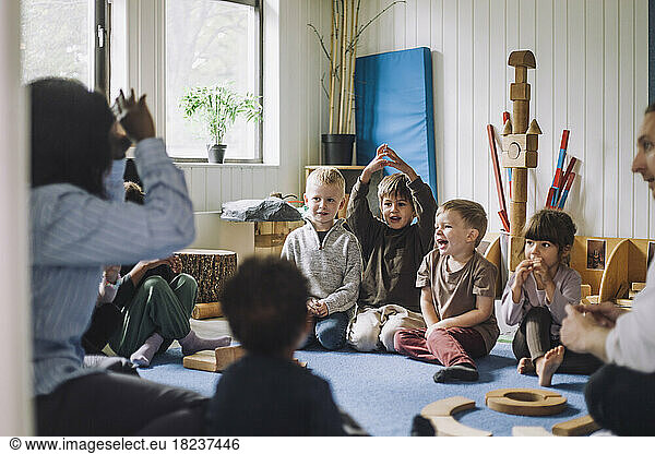 Female child care worker teaching boys and girls in day care center