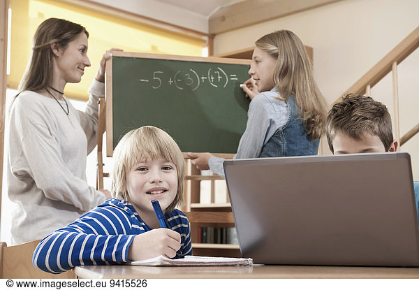 Female childcare assistant helping children by doing homework
