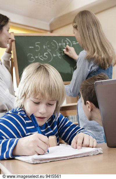 Female childcare assistant helping children by doing homework