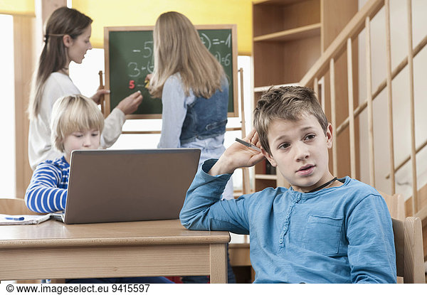 Female childcare assistant helping children by doing homework