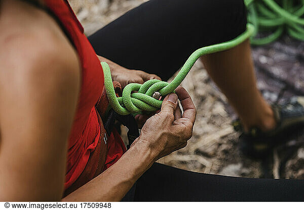Female climber adjusting ropes while preparing for rock climbing