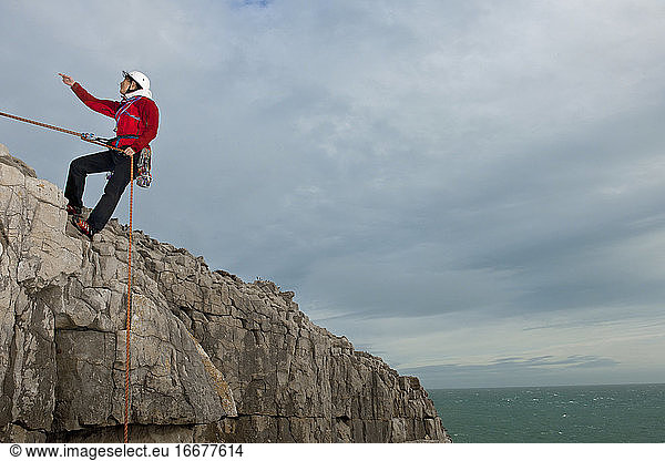 Female climber rappelling of seacliff in Swanage / England