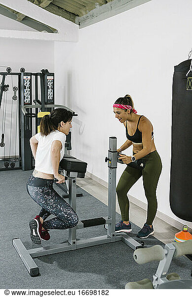 Female coach motivating mature woman while training in gym