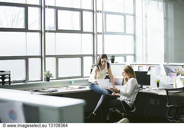 Female colleagues analyzing data at desk in office